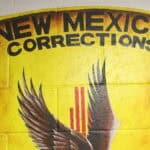 Sign for New Mexico Corrections Department featuring the state emblem and eagle, related to legal and correctional issues in New Mexico.
