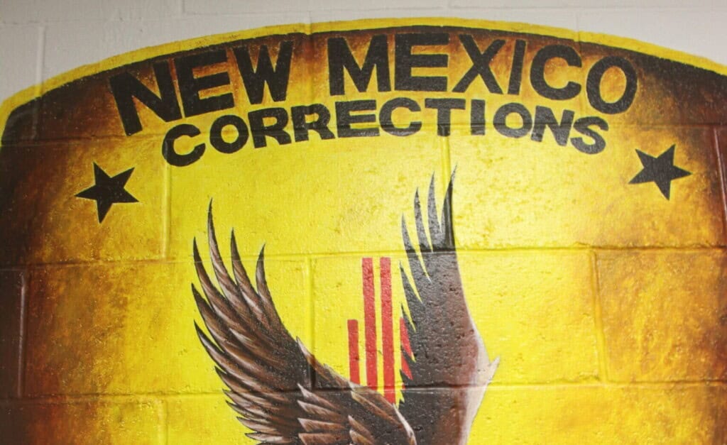 Sign for New Mexico Corrections Department featuring the state emblem and eagle, related to legal and correctional issues in New Mexico.