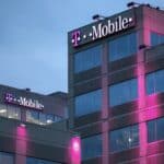 Modern T-Mobile office building illuminated with pink and purple lights at night, showcasing corporate branding and architecture.