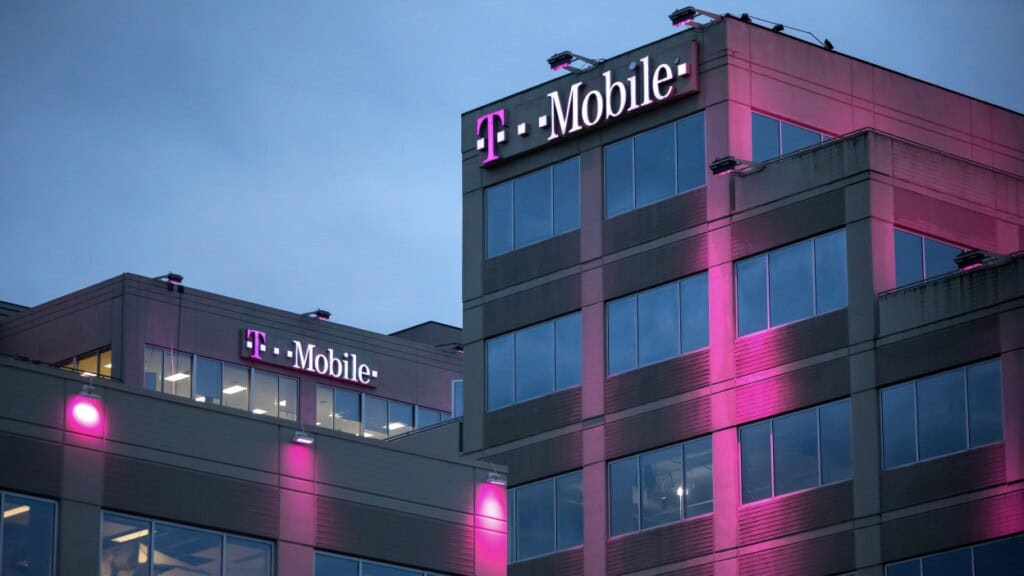 Modern T-Mobile office building illuminated with pink and purple lights at night, showcasing corporate branding and architecture.