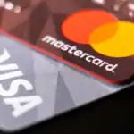 Close-up of Visa and Mastercard credit cards highlighting ATM usage and legal settlement context.
