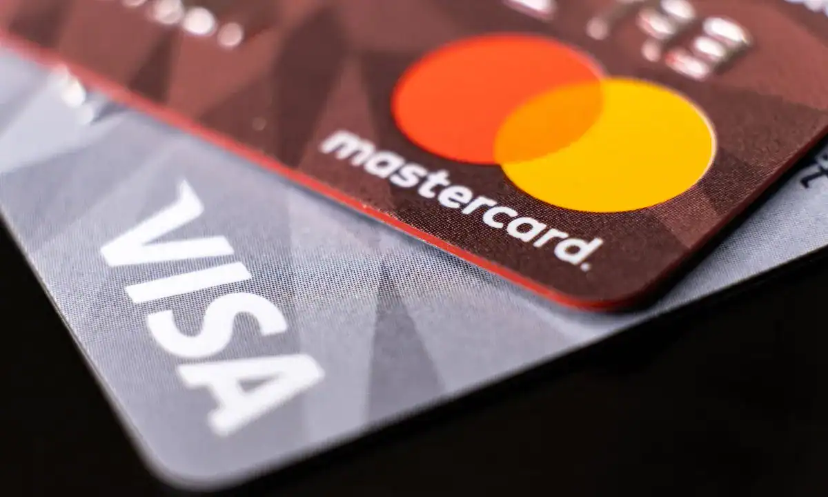 Close-up of Visa and Mastercard credit cards highlighting ATM usage and legal settlement context.