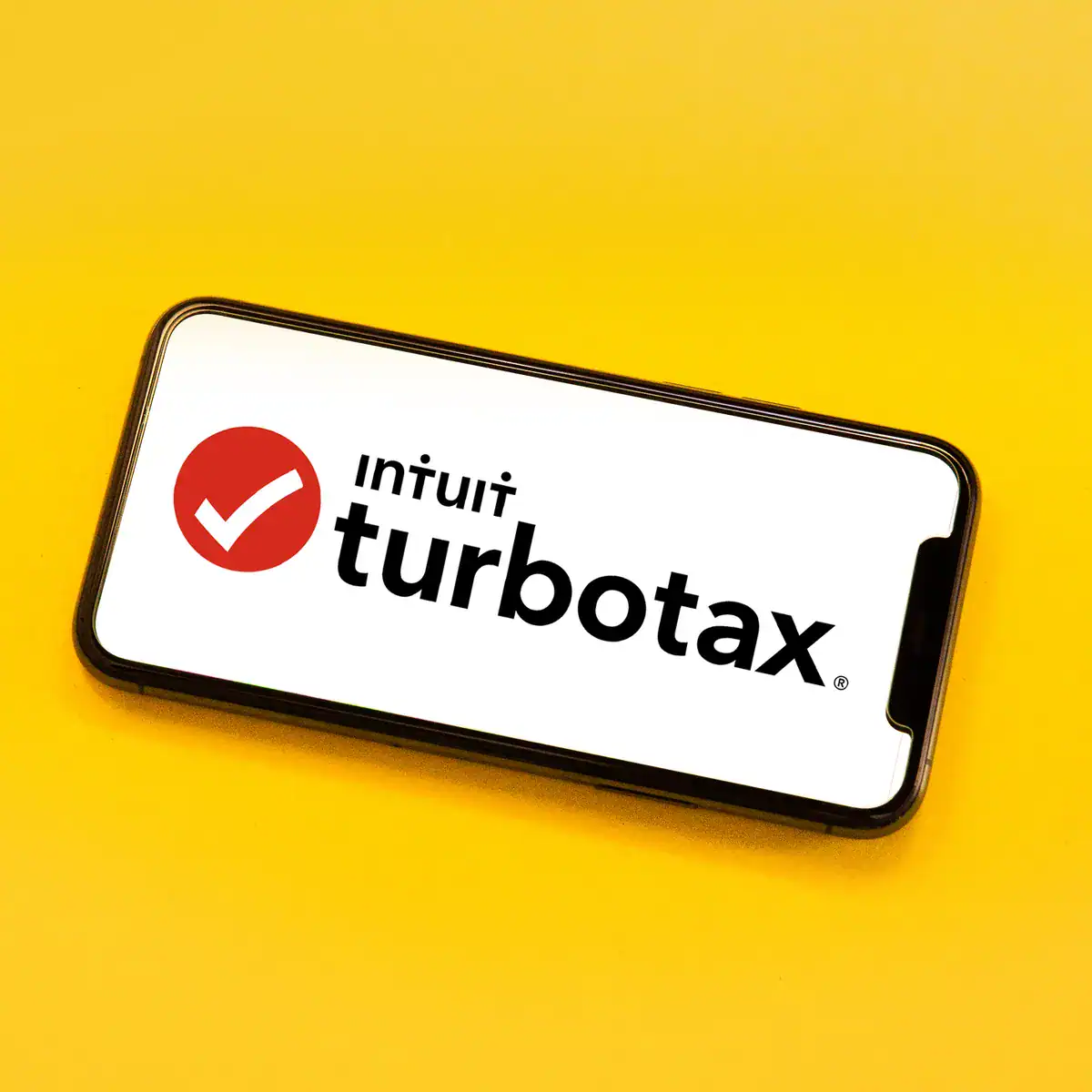 Smartphone displaying TurboTax logo on a yellow background, highlighting tax software issues and legal concerns for 2025.